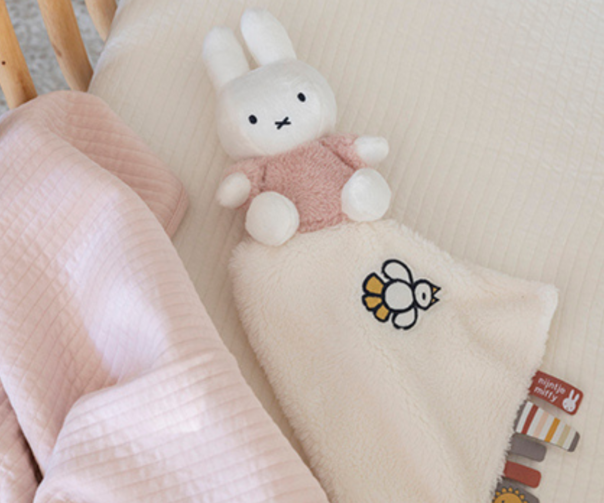 Beebi hoiab käes pehmet Miffy Fluffy Pink jänku kujulist kaisulappi.