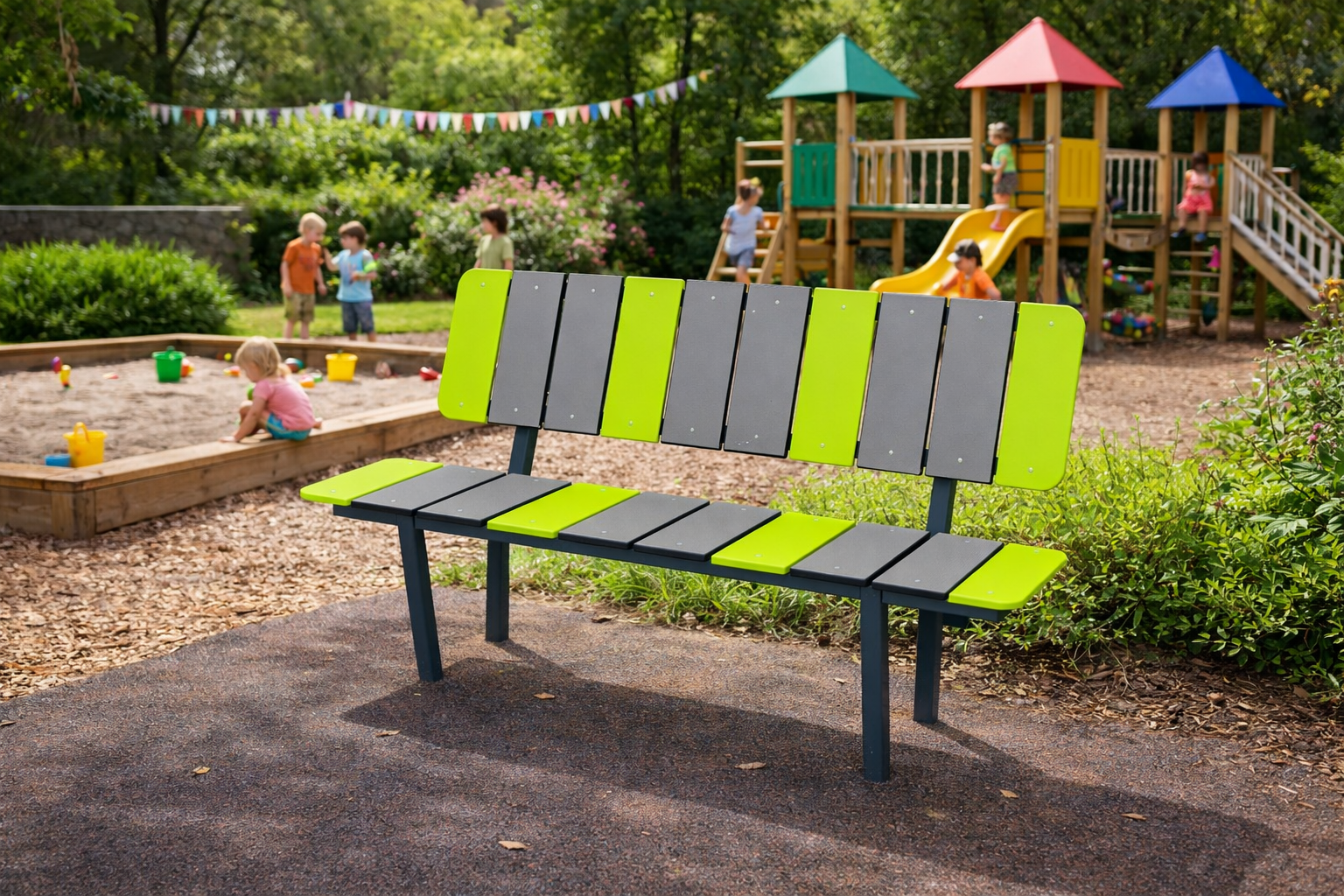 Rohelist ja halli tooni metallraamiga pink lasteaia mänguväljakul, taustal mängivad lapsed liivakastis ja ronimisatraktsioonidel värvilise mängulinnaku kõrval.