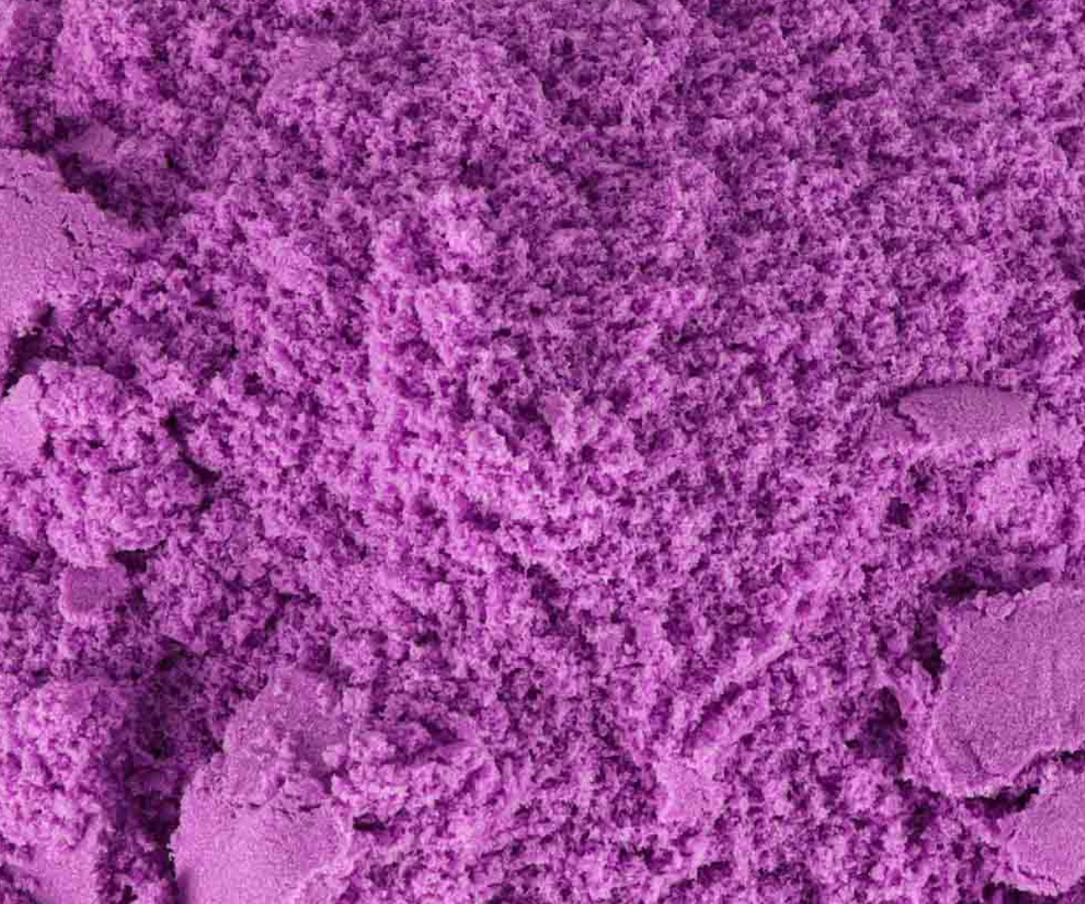 Lillast kineetilisest liivast vormitud kujundid ja tükid laual.