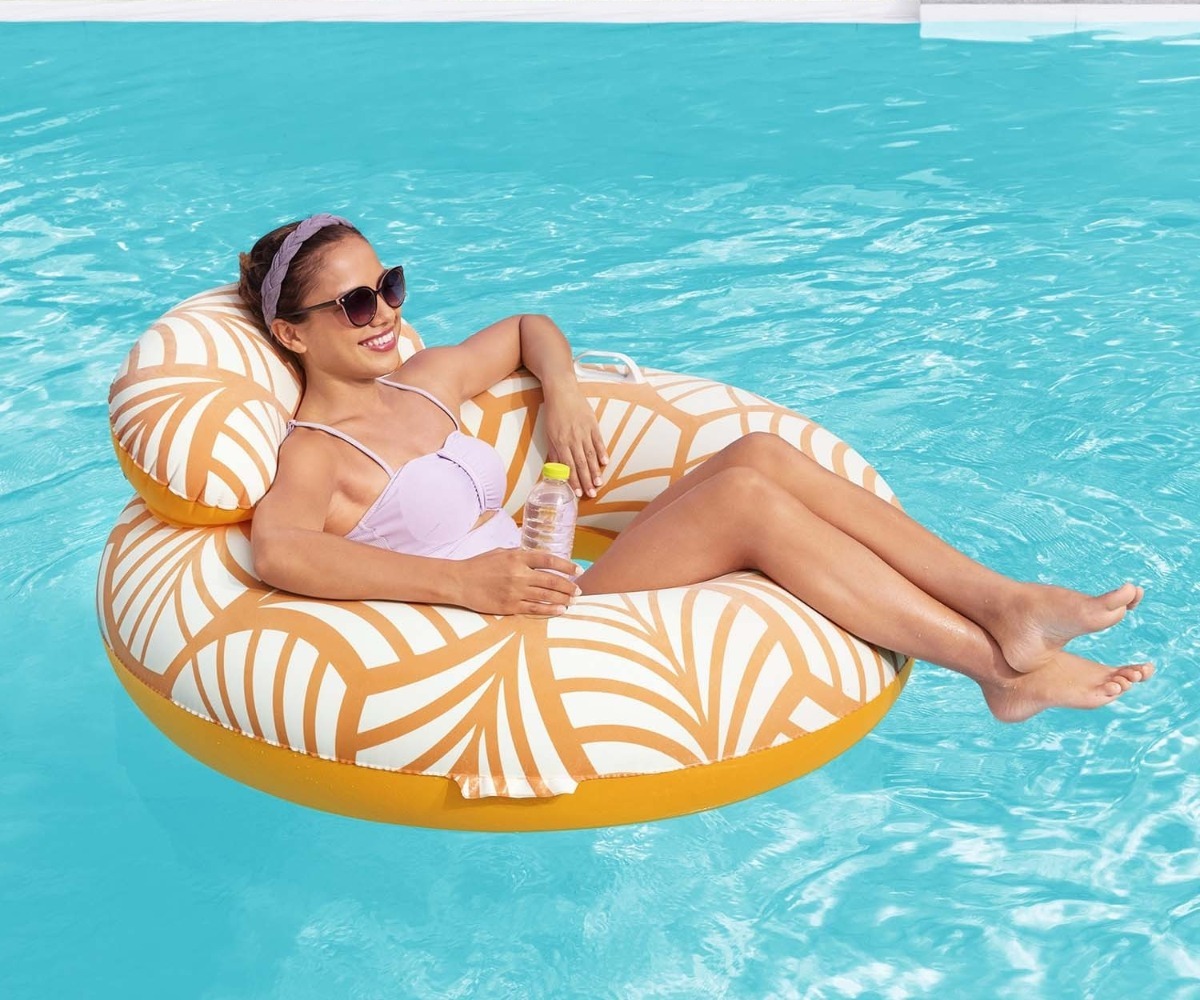 Naine ujumas ujumisrõngas seljatoega Bestway 117cm (43643) päikesepaistes