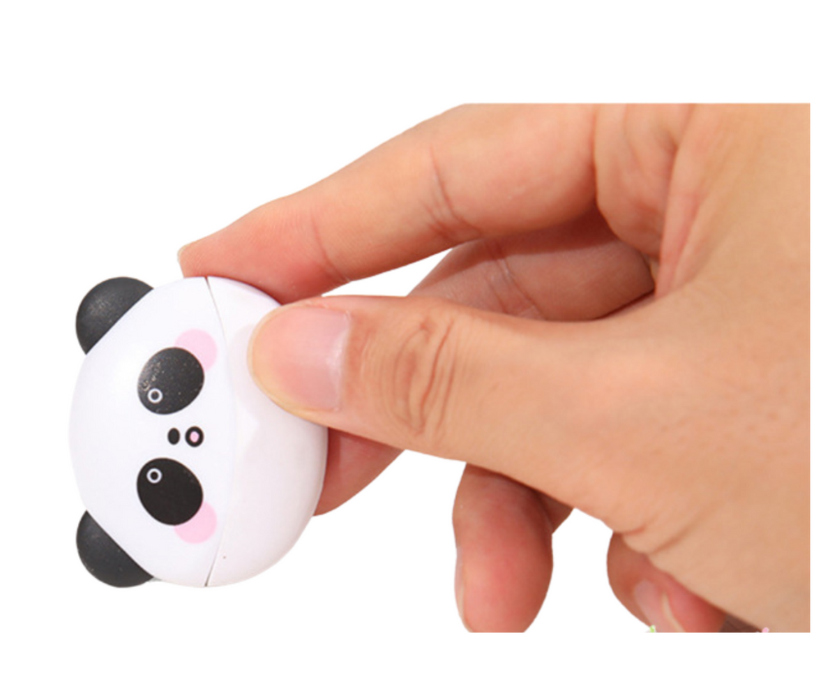 Lapse käsi hoiab panda kujulist kustutuskummi vihiku kohal