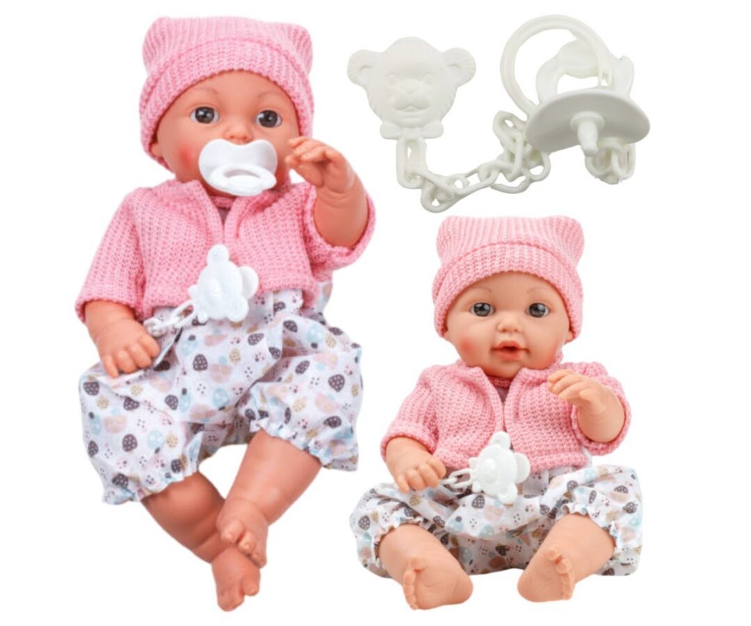 Beebinukk roosas kampsunis ja kõrvadega mütsiga, istumas ja naeratamas.