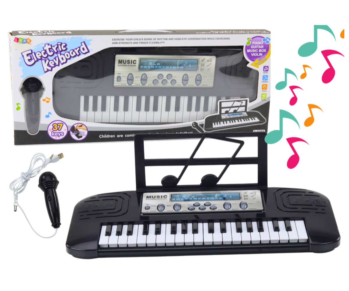 Must laste süntesaator mikrofoniga laual koos noodihoidjaga.