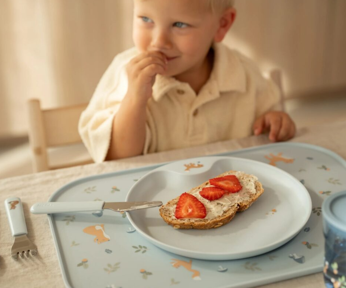Laps kasutamas Forest Friends söögialust iseseisvalt söömisel.