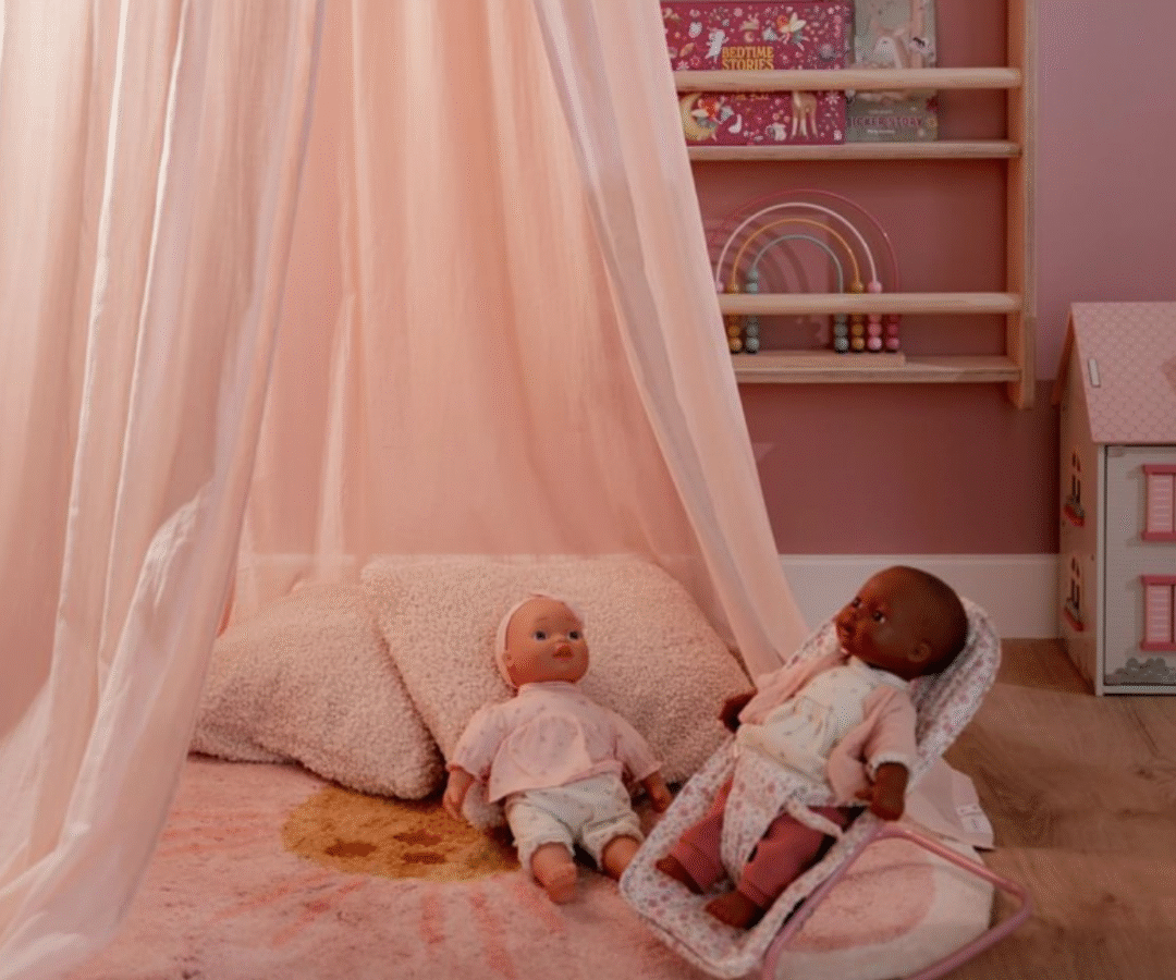 Õrn roosakas baldahhiin rippuvate tutidega, riputatud lakke lastetoa mängunurka.