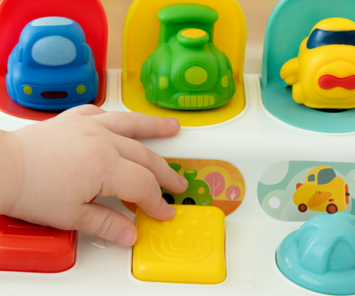 Värviline sensoorne mänguasi nelja peidetud autoga, mis hüppavad nupuvajutusel välja.