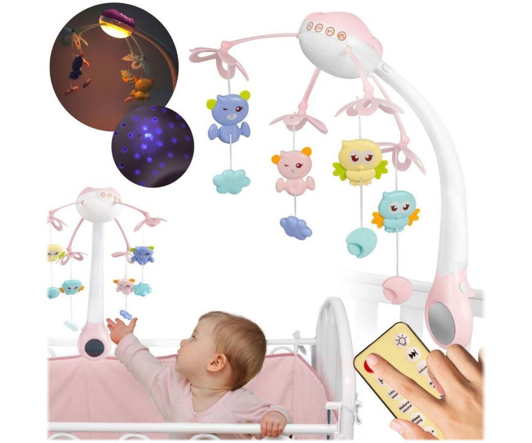 Roosa beebikarussell voodi küljes koos rippuvate mänguasjadega.