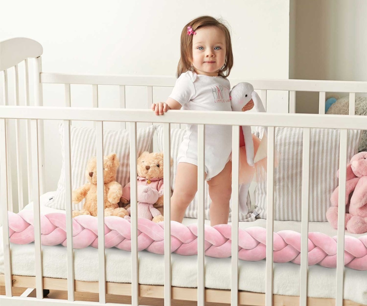 Tüdruk mängib voodipehmendusega Ricokids 3m – roosa, beebivoodis koos mänguasjadega.