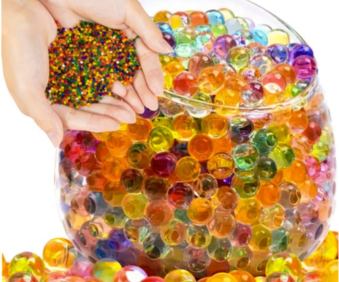 Hüdrogeelkuulid taimedele – mitmevärvilised kätes, värvilised kuulid suures kausis.