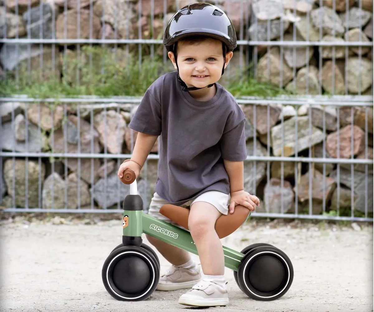 Laps erinevas keskkonnas Kolmerattaline jooksuratas Ricokids - esimene tasakaaluratas (1+), olles rõõmus ja turvakiivris.