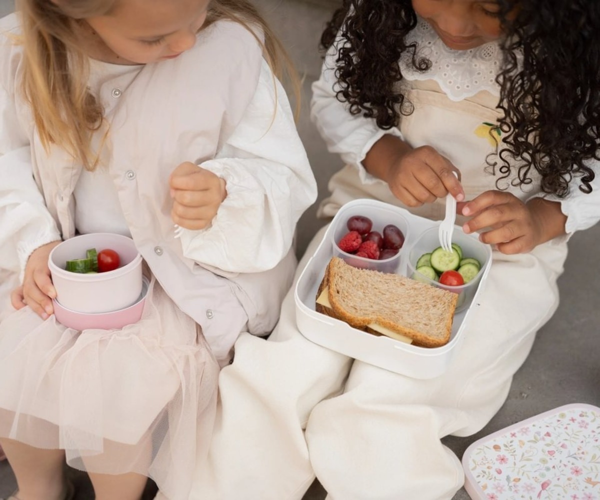 Kaks last naudivad koos toitu Suure laste toidukarbiga Fairy Wonders bentokarpidega.