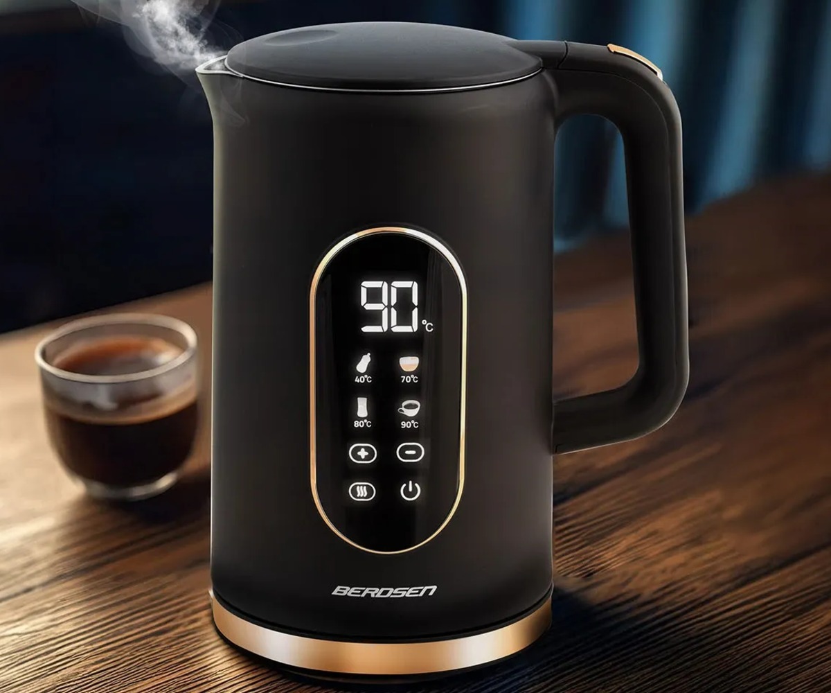 Veekeetja Berdsen BD-712 1,7L – must ja kuldne, aurav kuum tee koos, taustal kohviklaas.