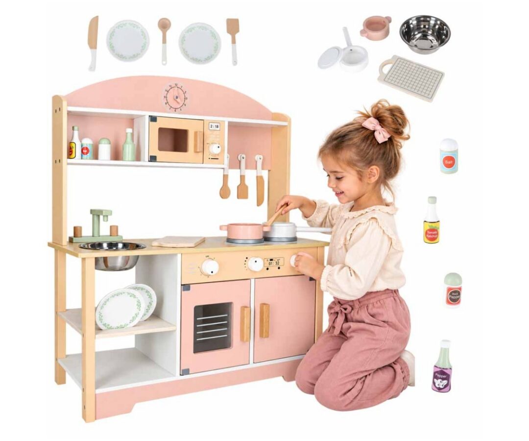 Puidust mänguköök lastele MODERN CLASSIC 82cm roosa, tüdruk toimetab köögis valmistades toitu.