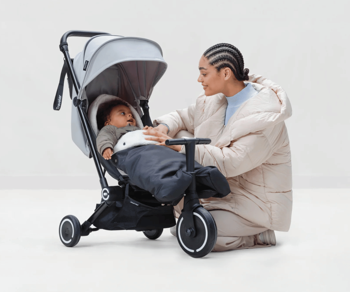 Ema hoiab oma last jalutuskärus, millel on SmarTrike Traveler soojakott - must, pakkudes soojust ja turvalisust.
